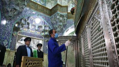 Trabajadores sanitarios iraníes desinfectan un santuario en la ciudad de Qom.