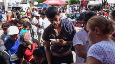 Los migrantes hondureños que participan en la caravana que se dirige a los Estados Unidos hacen cola para recibir comida durante una parada en su viaje, en Huixtla, estado de Chiapas, México.