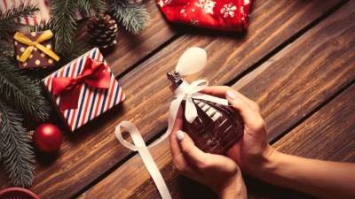 photo of the female hands holding perfume on the christmas decorations background