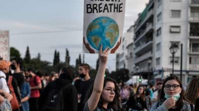 Una manifestante sostiene una pancarta que lee 'Ella no puede respirar', durante una manifestación este viernes en Atenas, Grecia, con motivo del día del Medio Ambiente. El mensaje hace alución a la muerte del afroamericano George Floyd, quien en su agonía de muerte dijo las palabras 'I can't breathe' ('no puedo respirar'). Las manifestaciones de indignación por este caso han tenido eco en Europa.