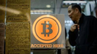 Un hombre camina frente a una tienda de Hong Kong que acepta pagos en bitcoins.