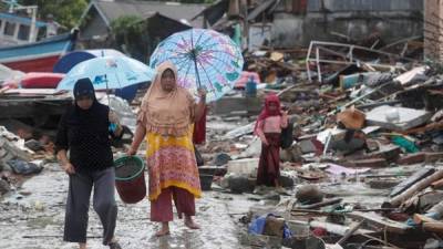 Los residentes locales caminan bajo la lluvia entre los escombros que tras el tsunami que golpeó el Estrecho de Sonda en Sumur, Banten, Indonesia. Según la Junta Nacional de Indonesia para el Manejo de Desastres (BNPB), al menos 373 personas murieron y 1.459 resultaron heridas tras el tsunami que golpeó la zona el 22 de diciembre. EFE.
