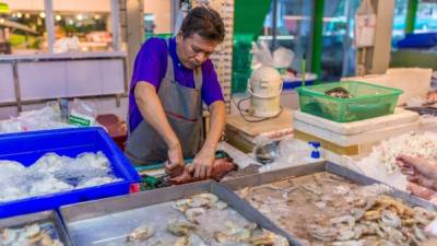 CONSUMO. Un trabajador en un mercado limpia productos acuícolas para la venta.