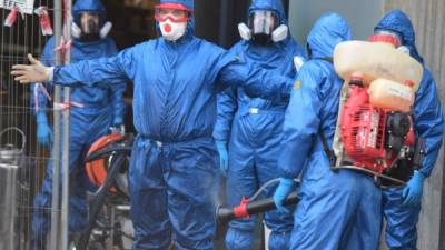 Unos hombres en Italia se protegen con un traje especial para evitar el contagio con coronavirus. Foto: AFP
