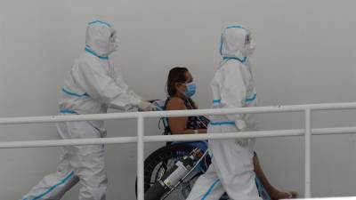 Personal sanitario mientras ingresa a una mujer a una unidad especializada para pacientes covid-19 en un hospital de San Salvador (El Salvador).