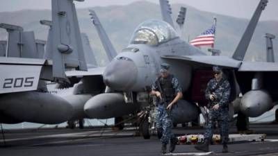 Dos marines patrullan junto a un caza F-18. EFE/Archivo