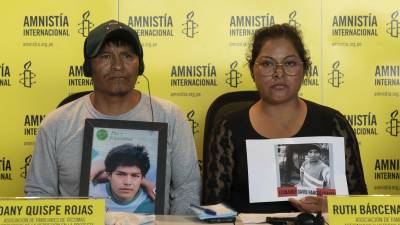 Familiares de dos de las víctimas en las violentas protestas muestran sus fotografías en un evento de Amnistía Internacional en Lima.