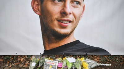 Flowers and candles are left with the front page of French sports daily newspaper 'L'Equipe' reading 'The disappearance of a warrior' next to a portrait of Emiliano Sala in front of the entrance of the FC Nantes football club training center La Joneliere in La Chapelle-sur-Erdre on January 23, 2019, two days after the plane of Argentinian forward vanished during a flight from Nantes in western France to Cardiff in Wales. - The 28-year-old Argentine striker is one of two people still missing after contact was lost with the light aircraft he was travelling in on January 21, 2019 night. Sala was on his way to the Welsh capital to train with his new teammates for the first time after completing a £15 million ($19 million) move to Cardiff City from French side Nantes on January 19. (Photo by LOIC VENANCE / AFP)