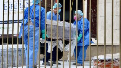 Empleados usan trajes de seguridad para llevar el ataúd de una persona que murió por el nuevo coronavirus en Ecuador. Foto: AFP