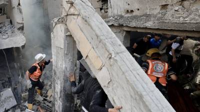Los rescatistas buscan supervivientes entre los escombros de un edificio alcanzado por un ataque aéreo israelí en Khan Yunis, en el sur de la Franja de Gaza, el 24 de octubre de 2023.