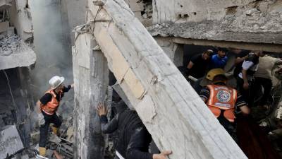 Los rescatistas buscan supervivientes entre los escombros de un edificio alcanzado por un ataque aéreo israelí en Khan Yunis, en el sur de la Franja de Gaza, el 24 de octubre de 2023.