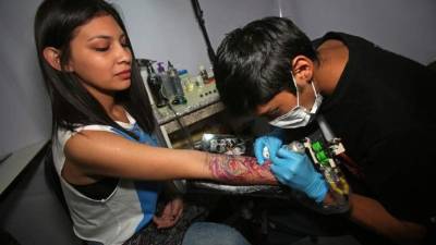 Un joven fue registrado este viernes al tatuar a una mujer, durante la I Convención de Arte Corporal Ajayu Tattoo, en La Paz (Bolivia). EFE