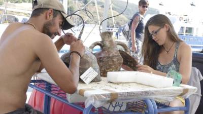 Fotografía de unos arqueólogos limpiando objetos extraídos de uno de los hallazgos del archipiélago de Furni, en el mar Egeo oriental. EFE