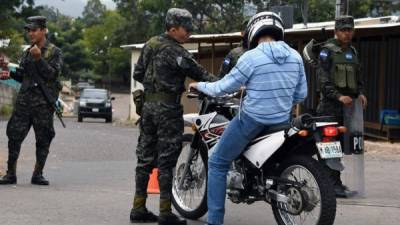 Honduran Army soldiers stop a motorcyclist at a checkpoint during a security operation near the Supreme Electoral Tribunal (TSE) facilities in Tegucigalpa on December 06, 2017.Honduras appeared set for a recount of its election after incumbent President Juan Orlando Hernandez welcomed a demand by the opposition to re-open ballot boxes, a week into a crisis triggered by rigging claims. / AFP PHOTO / ORLANDO SIERRA