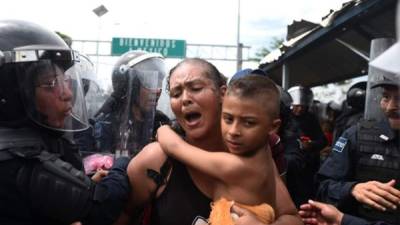 Una mujer lucha por entrar a México con su niño en brazos.