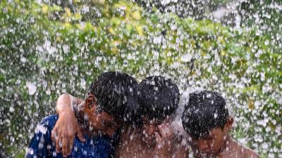 Tres menores se refrescan durante una ola de calor que golpea fuertemente a la India.