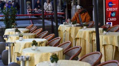 Un hombre con una máscara protectora se sienta hoy en un bar vacío cerca de la Piazza del Duomo en el centro de Milán, después de que COVID-19, el nuevo coronavirus, se extendió a Italia. AFP.