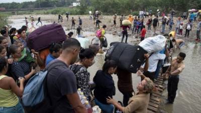 People cross from Cucuta in Colombia back to San Antonio del Tachira in Venezuela after buying goods to resell, through an improvised bridge on a 'trocha', an illegal trail on the border between the two countries near the Simon Bolivar international bridge, on March 21, 2019. - Venezuela is in the grip of a humanitarian crisis due to shortages of food and medicine exacerbated by hyperinflation. (Photo by Juan Pablo BAYONA / AFP)