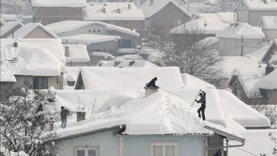 Hombres quitan la nieve acumulada en los tejados tras las intensas nevadas de los últimos días, en la localidad de Zhur, al sur de Kosovo. EFE/Archivo
