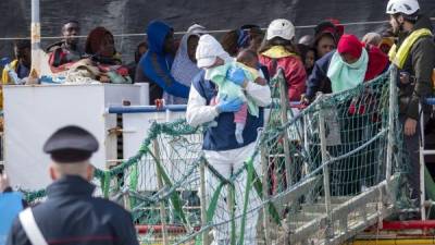 Migrants rescued in the Mediterranean sea disembark from the Sea Watch NGO's ship on February 27, 2020 in the port of Messina, Sicily. - Migrants are checked for coronavirus as they disembark from the NGO Sea Watch in the port of Messina. (Photo by Giovanni ISOLINO / AFP)
