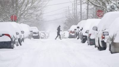 SEATTLE, WA - FEBRUARY 13: A jogger makes their way across a snowy street on February 13, 2021 in Seattle, Washington. A large winter storm dropped heavy snow across the region. David Ryder/Getty Images/AFP== FOR NEWSPAPERS, INTERNET, TELCOS & TELEVISION USE ONLY ==