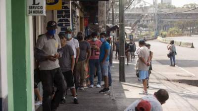 Decenas de personas hacen fila para utilizar el cajero automático antes del horario de prohibición bajo la vigilancia de la Policía municipal, que inspecciona que los negocios cierren a las 11 de la mañana en punto en San Lucas, Sacatepéquez. EFE/Esteban Biba