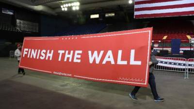 Voluntarios mueven un eslogan en el que se lee 'termina el muro', previo a la llegada de Trump a El Paso, Texas./AFP.