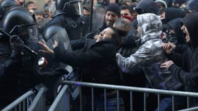 Miembros de la policía regional catalana intentan mantener a manifestantes detrás de las barricadas de control. AFP