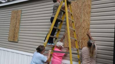 PORT ST. JOE, FL - OCTOBER 09: Linda Collins (on ladder) is assisted by friends as she places plywood over the windows of her home in preparation for the arrival of Hurricane Michael on October 9, 2018 in Port St. Joe, Florida. The hurricane is forecast to hit the Florida Panhandle at a possible category 3 storm. Joe Raedle/Getty Images/AFP