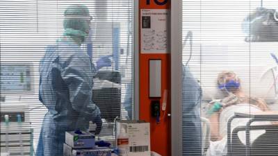Trabajadores médicos usan una marca facial y equipo de protección para dirigirse a un paciente con coronavirus. Foto: AFP