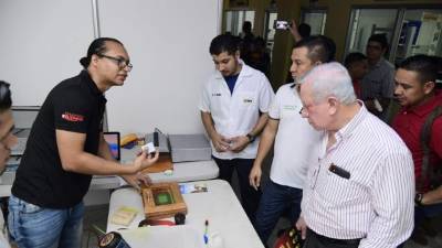 El presidente Roger Valladares y el director de la facultad observan los proyectos.