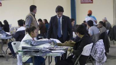 El magistrado del Tribunal Supremo Electoral, Enrique Ortez (c), supervisa hoy, martes 3 de diciembre de 2013, el trabajo de revisión de las actas de votación de las pasadas elecciones presidenciales a petición de la candidata del izquierdista Libertad y Refundación (Libre), Xiomara Castro, en las bodegas del TSE en Tegucigalpa. EFE