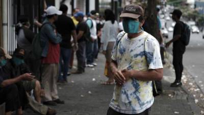 Personas con estatus de refugiado y de bajos recursos económicos esperan para recibir víveres en San José. Foto: EFE