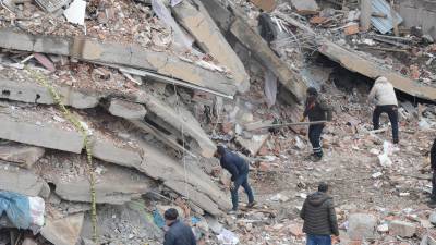 Volulntarios buscan sobrevivientes entre los escombros de un edificio derrumbado en Turquía.