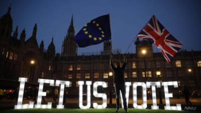 (FILES) In this file photo taken on March 27, 2019 An anti-Brexit activist waves the Union and EU flags near the Houses of Parliament in central London, during a demonstration calling for a second referendum on Britain leaving the EU. - Britain is set to leave the European Union on at 2300 GMT on January 31, 2020, 43 months after Britons voted in the June 2016 referendum to leave the EU, ending more than four decades of economic, political and legal integration with its closest neighbours. (Photo by Tolga AKMEN / AFP)