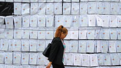 Fotografía del 26 de diciembre de 2025 que muestra a una mujer caminando frente a copias de actas electorales a las afueras del Centro Logístico Electoral (CLE) en Tegucigalpa (Honduras).