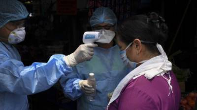 Personal médico le toma la temperatura a una mujer en El Salvador. Foto: AFP