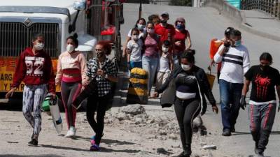 Un grupo de ciudadanos venezolanos camina cerca de los buses que fueron rentados por ellos mismos para regresar a su país ante la emergencia por el coronavirus COVID-19, pero que fueron devueltos por las autoridades colombianas el pasado domingo en Bogotá. EFE/Carlos Ortega/Archivo