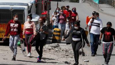 Un grupo de ciudadanos venezolanos camina cerca de los buses que fueron rentados por ellos mismos para regresar a su país ante la emergencia por el coronavirus COVID-19, pero que fueron devueltos por las autoridades colombianas el pasado domingo en Bogotá. EFE/Carlos Ortega/Archivo