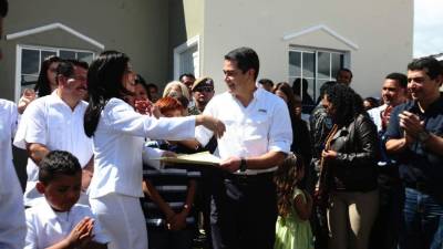 Una beneficiada recibe del presidente Juan Orlando Hernández el título de propiedad en actos de inauguración.