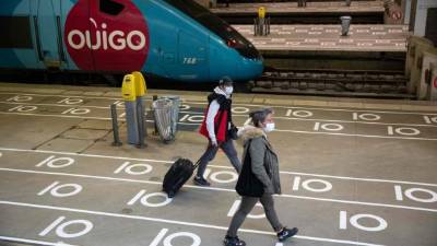Los viajeros que usan una máscara protectora caminan junto a un tren pasando las marcas de distanciamiento social en el suelo en la estación de tren Gare Montparnasse en París el 12 de mayo de 2020, después de que Francia alivió las medidas de bloqueo tomadas para frenar la propagación de la pandemia COVID-19, causada por la nuevo coronavirus. / AFP / Thomas SAMSON
