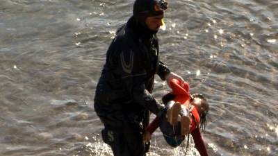 Un buzo saca del agua el cadáver de una niña que pereció en la costa de Lesbos. Foto: AFP