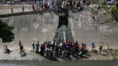 Desesperados, decenas de venezolanos se lanzaron a las aguas del contaminado río Guaire para recoger agua./AFP.
