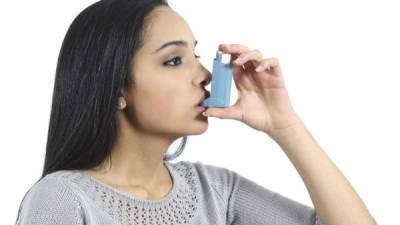 Asthmatic arab woman breathing from a inhaler isolated on a white background