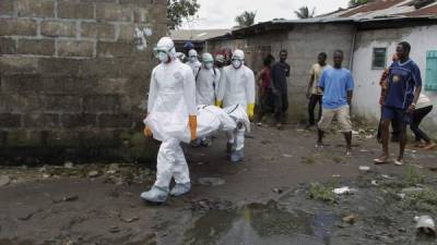 Varios operarios trasladan el cadáver de una supuesta víctima del virus del ébola en una barriada de Logan, afueras de Monrovia, Liberia.