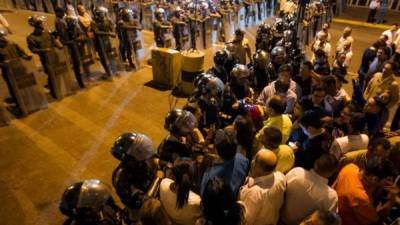 Miembros de la Policía Nacional Bolivariana (PNB) hablan con personas mientras custodian el edificio del Servicio Bolivariano de Inteligencia Nacional (SEBIN) hoy, jueves 19 de febrero de 2015, en Caracas (Venezuela).