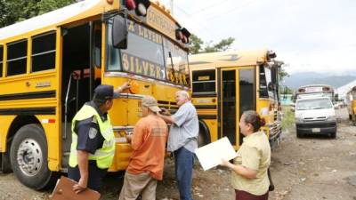 Dos propietarios de buses conversan con uno de los inspectores durante la revisión físico-mecánica para asegurarse de que tienen todos los documentos en orden. Foto: Amílcar Izaguirre