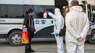 Personal sanitario desinfecta a pacientes que regresan del hospital de Wuhan previo a su ingreso a una región en cuarentena./AFP.