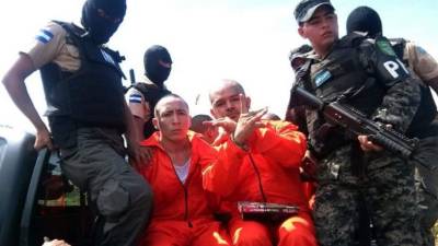 Dos líderes de la Mara 18 hacen señales hacia las cámaras durante su traslado al a prisión de máxima seguridad en Honduras. (Foto AFP/Archivo).