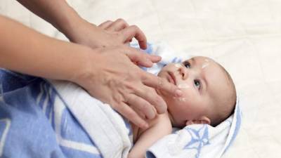 Applying moisturizing cream on face of baby after bath